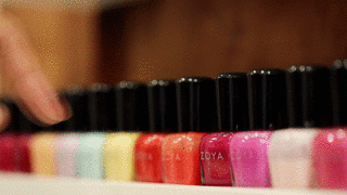 A row of nail polishes, a person selects their color