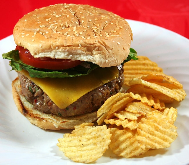 Photo of a large cheeseburger with potato chips