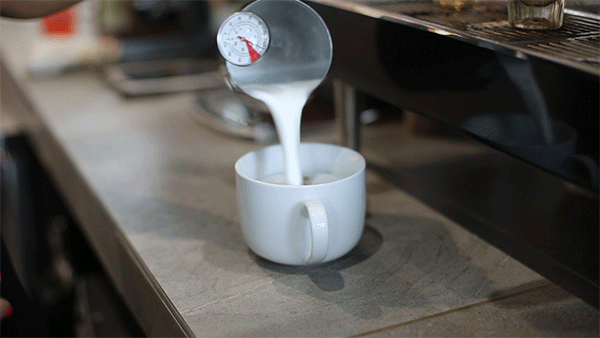 Barista pouring steamed milk into a cup