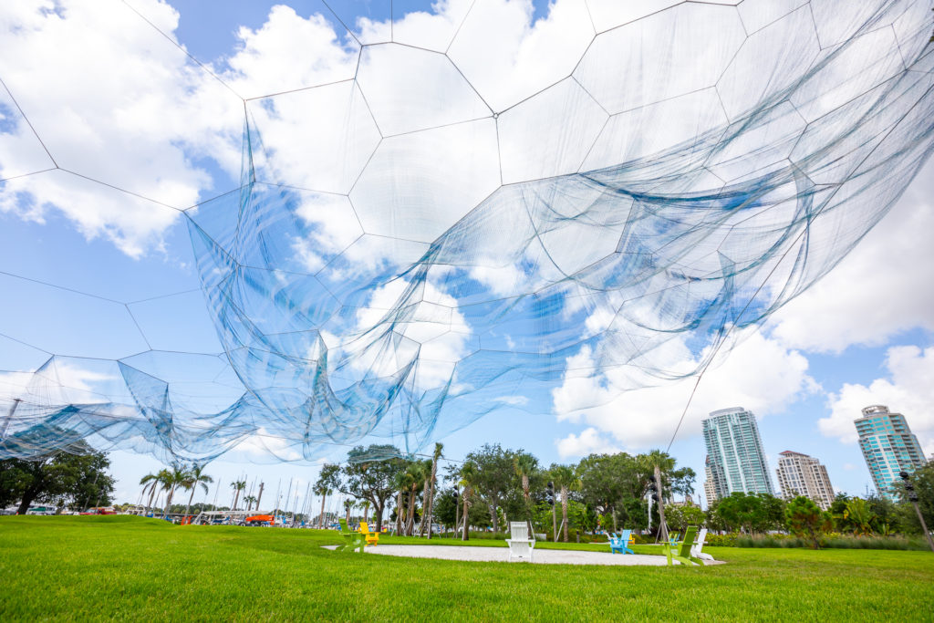 A large net art installation over a large patch of green space