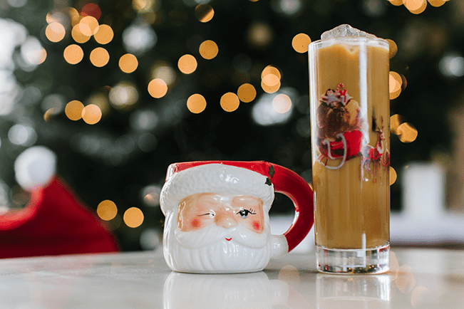 Santa mug situated next to a tall, skinny cocktail glass. 