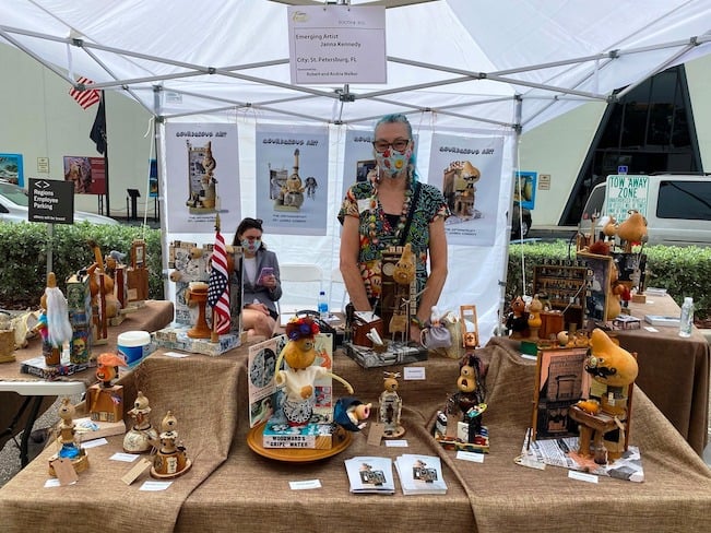 Assorted sculptures and craft art pieces displayed under a tent