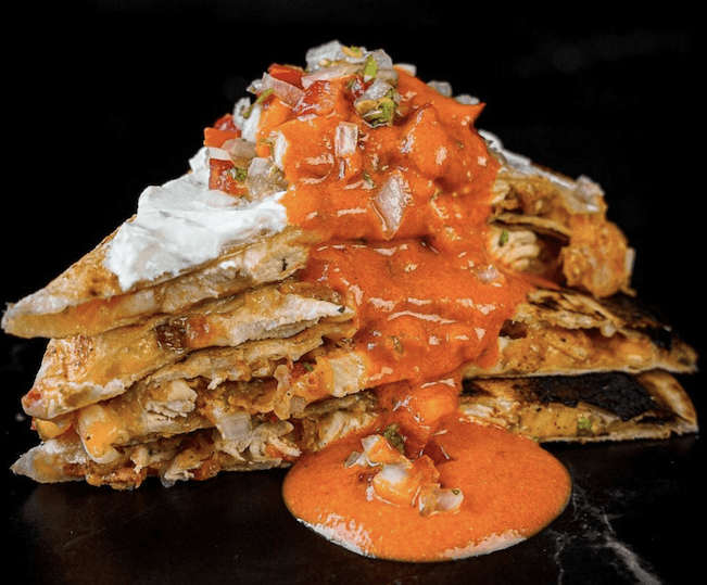 chicken quesadilla covered in spicy red sauce and ranch dressing