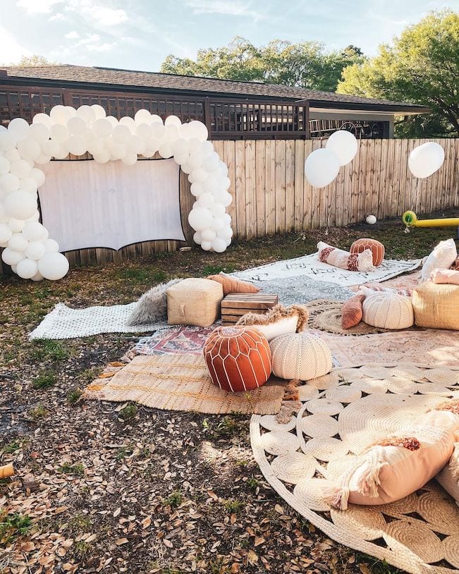 A screen projector and boho picnic set up in a backyard