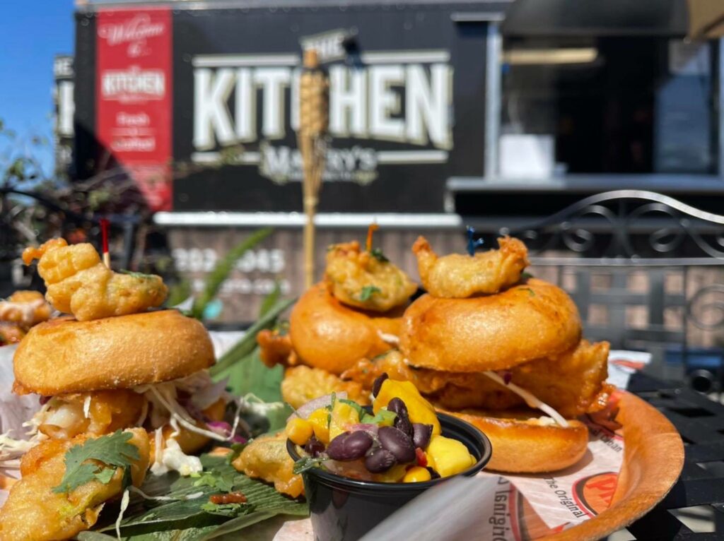 three slider sandwiches plated in front of a food truck