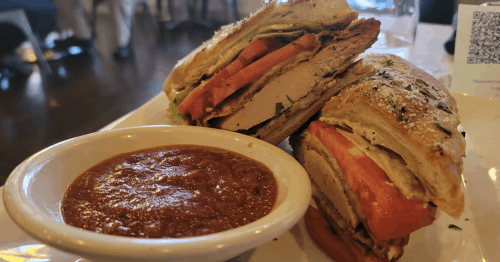 large sandwich with a red dipping sauce on the side