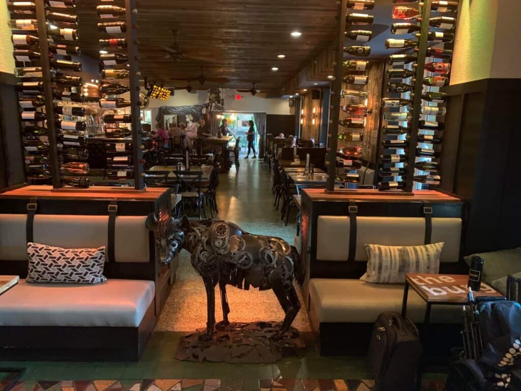 steel hyena sculpture inside a lobby with wine racks behind it.