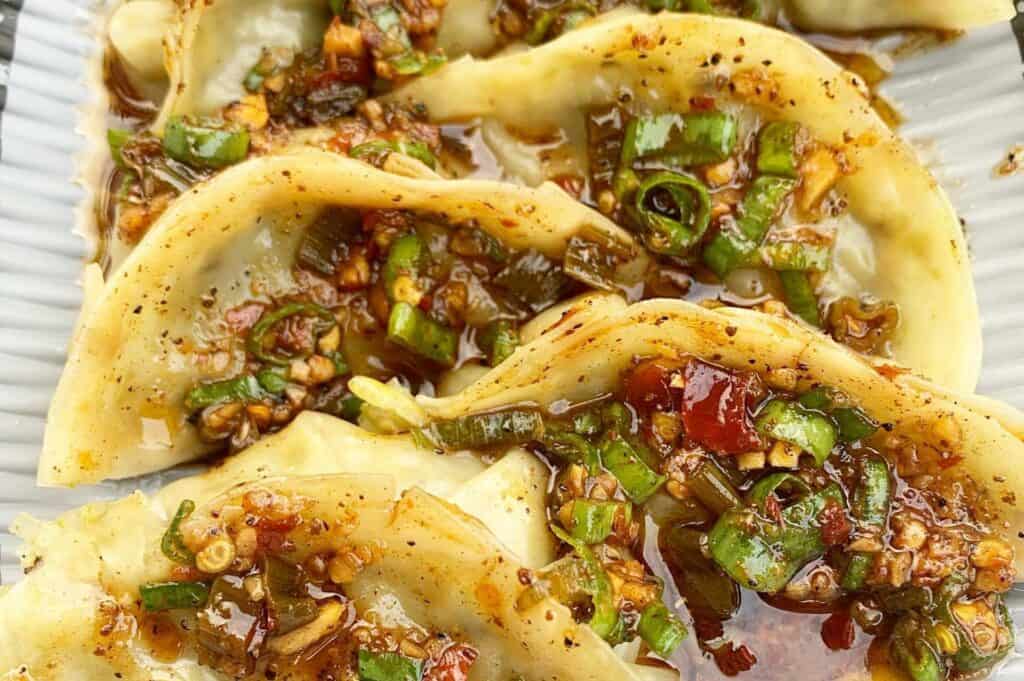 dumplings covered in sauce and green vegetables 