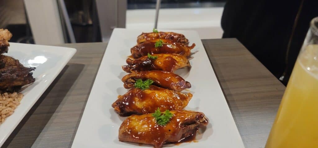 plate of sauce covered wings with green garnish 