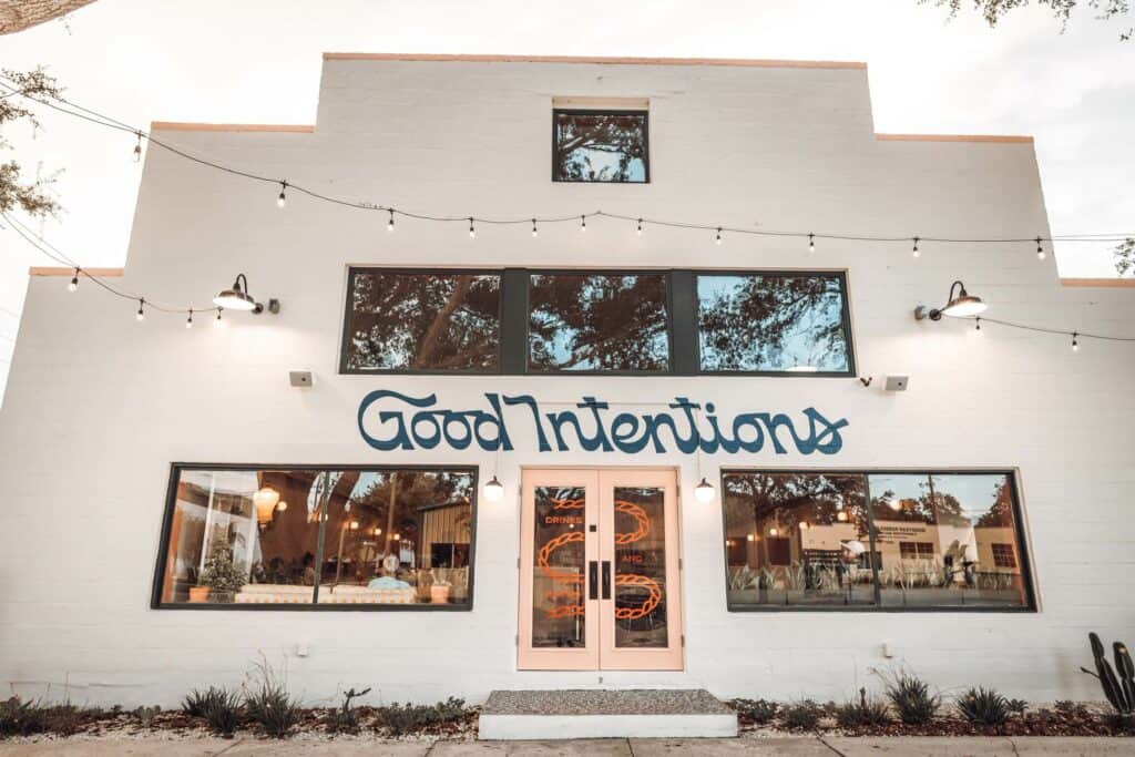 Exterior of white building with pink doors and "Good Intentions" signage